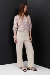 Pantalón de lino color marrón oscuro, tiro alto, corte recto y holgado, con pinzas delanteras y pespuntes a contratono en blanco.