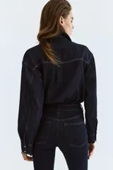 Jean de cinco bolsillos en denim oscuro, con leve elasticidad. Corte ajustado de tiro alto, ceñido desde la cintura hasta las piernas extraajustadas.