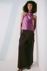 Top halter confeccionado en tejido satinado de color lila, con escote fluido y hombros descubiertos. Presenta cierre en la espalda con botón oculto.