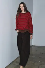 Jersey de punto con diseño a rayas horizontales en color rojo y marrón. Presenta cuello redondo, manga larga con puños ajustados y ruedo acanalado.