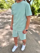 Conjunto deportivo para hombre compuesto por una remera de manga corta con cuello redondo y un short con cordón ajustable en la cintura, ambos en color verde menta.