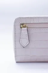 Billetera chica de cuero negro con textura tipo cocodrilo, cierre exterior, bolsillo para monedas con cierre en la parte trasera, múltiples ranuras para tarjetas y billetes, y forro rojo.