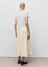 Falda midi de tiro medio color beige, con diseño evasé y detalles de tablas frontales. Cuenta con cierre de cremallera lateral.