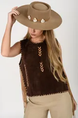 Chaleco de cuero marrón oscuro, sin mangas, con detalles de costuras decorativas y flecos largos en los laterales. Presenta cuello redondo y diseño de inspiración artesanal o western.