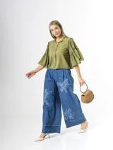 Pantalón wide leg de denim azul, con cintura elástica y apliques de flores grandes en tela vaquera en las piernas.
