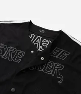 Camisa deportiva de estilo béisbol confeccionada en tejido mesh negro. Presenta cuello en V, cierre frontal con botones a presión, mangas cortas con franjas laterales blancas y bordado con la palabra Breaker y el número 96 en el frente.