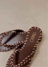 Sandalias planas de cuero marrón con costuras decorativas en tono tostado alrededor de las tiras y la suela, marca Criado.