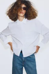Camisa de algodón con estampado de rayas verticales, cuello solapa y puños en color blanco a contraste. Presenta cierre frontal con botones, bolsillo de plastrón en el delantero y bajo asimétrico.