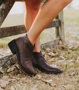 Bota corta de cuero vacuno con acabado metalizado y textura de reptil. Presenta punta fina, cierre lateral interno y taco cuadrado de madera.