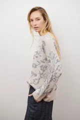 Buzo de tejido de punto en color marrón con un patrón ornamental floral en color celeste. Presenta cuello redondo, mangas largas y un corte holgado.