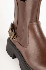 Botas de caña baja color negro, símil cuero, con pieza elastizada en sus laterales, aplique de hebilla metálica y plataforma de 5cm de alto.