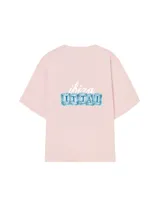 Remera rosa de corte holgado con estampado en la espalda que incluye la palabra 'ibiza' en letras cursivas y la frase 'IT TAI' en letras mayúsculas sobre cubos de hielo.