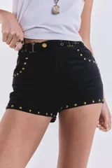 Short corto negro de gamuza con tachas doradas en el ruedo y cinturón con hebillas metálicas.