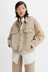 Campera de jean estilo trucker, color beige, con cierre frontal de botones metálicos, bolsillos con solapa en el pecho y costuras reforzadas.