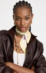 Pañuelo cuadrado de material sintético con estampado floral en tonos crema, verde y violeta, con bordes enmarcados y acabado fino.