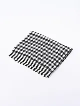 Bufanda rectangular con diseño a cuadros tipo pata de gallo en blanco y negro, con flecos en los extremos.