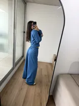 Conjunto deportivo de dos piezas color azul, compuesto por un buzo de cuello redondo y mangas largas, y un pantalón de corte ancho con cintura elástica. El buzo presenta un diseño reversible con costuras visibles.