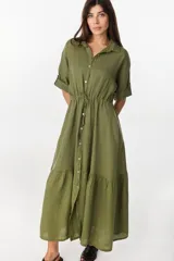 Vestido midi verde militar de lino italiano, corte relajado tipo camisero con mangas cortas con martingala, cierre frontal de botones y jareta ajustable en la cintura con volado fruncido en el bajo.