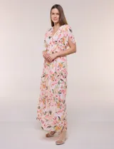 Vestido maxi de gasa con estampado floral en tonos rosados, amarillos y verdes, escote en V cruzado, mangas cortas amplias con abertura y falda larga con niveles fruncidos.