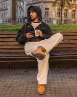 Canguro negro con capucha y cierre frontal, con texto bordado en el pecho y bolsillos laterales.