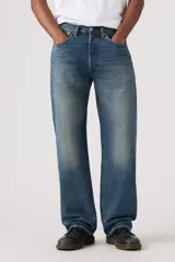 Jeans de corte holgado y tiro medio, con diseño clásico de cinco bolsillos y cierre de botones. Presentan un lavado azul medio con efecto desgastado en los muslos.