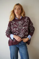 Buzo de tejido de punto en color marrón con un patrón ornamental floral en color celeste. Presenta cuello redondo, mangas largas y un corte holgado.