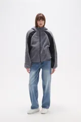 Campera de abrigo de tejido polar (tipo sherpa) color gris oscuro, con capucha y cierre frontal. Presenta paneles de color negro en los hombros y mangas, ribeteados con un vivo de color claro.