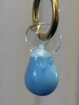 Aros tipo argolla dorada con dije colgante de vidrio soplado en forma de lágrima, con diseño marmolado en tonos celeste y blanco.