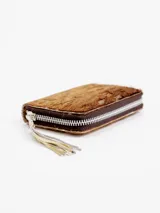 Billetera de cuero con textura de pelo animal print, diseño compacto y cierre perimetral con tirador de flecos.
