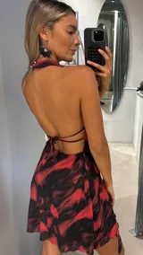 Vestido corto con estampado abstracto en tonos rojo y negro, con escote halter y cuello drapeado.