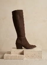 Bota de caña alta confeccionada en cuero vacuno color marrón, con taco cuadrado de 6 cm y suela de caucho antideslizante.