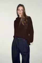 Pantalón de denim azul oscuro, tiro alto, con pinzas delanteras que generan volumen en la cadera y pernera ancha y recta. Presenta cierre frontal y bolsillos laterales.