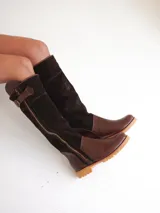 Botas altas de cuero marrón combinadas con gamuza blanca con estampado de vaca, forradas en cuero y con cierre de bronce.