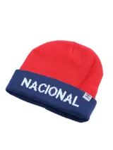 Gorro de lana tipo beanie con vuelta, de color rojo con la parte inferior en azul marino. Presenta la palabra 'NACIONAL' tejida en blanco en el frente y una etiqueta pequeña con el logo de Umbro en el borde.