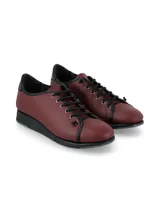 Zapatillas de cuero napa color bordó, con cordones y suela anatómica de goma negra. Presenta detalles en color negro en la cordonera, el borde superior y el talón.