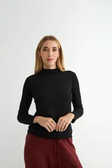 Polera de cuello alto y manga larga, confeccionada en tejido de punto fino de color negro con diseño liso y corte ajustado.