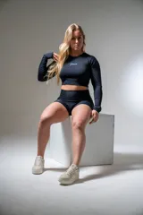 Remera deportiva de lycra negra con estampado de cebra, corte crop top, mangas largas con orificio para el pulgar y logo estampado en blanco.