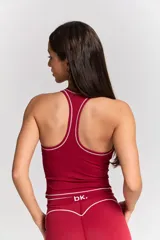 Conjunto deportivo compuesto por un top de tirantes finos con escote redondo y un pantalón de pierna ancha, ambos en color bordó con detalles de costuras en contraste blanco. El top presenta el logo 'bk.' estampado en el frente.