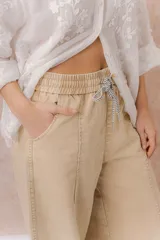 Pantalón de denim liviano color beige, de calce amplio y relajado con pierna recta. Cuenta con cintura elastizada, cordón regulable, bolsillos laterales y costuras delanteras verticales que estilizan la silueta.