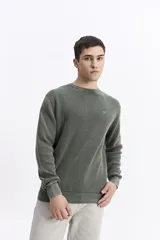 Sweater de hombre con textura waffle, color verde oliva desgastado (acid wash), cuello redondo y puños y ruedo acanalados. Presenta un pequeño logo bordado en el pecho.