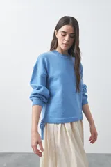 Sweater de tejido liviano con silueta relajada, hombros caídos y mangas largas con puños ajustados. Presenta cuello redondo y lazos ajustables en el bajo.