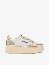 Zapatillas de plataforma Autry Medalist, con diseño inspirado en el tenis de los años 80. Presentan una combinación de cuero blanco y cuero laminado color platino, con microperforaciones en la puntera para mayor transpirabilidad y suela de plataforma alta en tono crema.