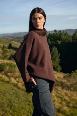 Sweater de tejido de punto suave en color beige, con silueta holgada, cuello alto y mangas tres cuartos con puños definidos.