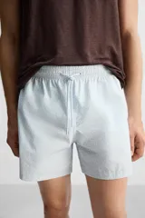 Short de baño celeste con estampado geométrico paisley, cintura elástica con cordón ajustable, bolsillos laterales y bolsillo trasero.