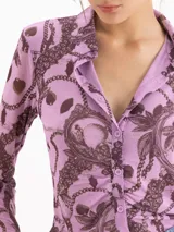 Camisa de mesh elastizado color azul con estampado de cadenas, de manga larga y suave transparencia, con drapeado en el centro delantero.