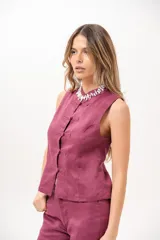 Chaleco sin mangas de color magenta, con cuello redondo y cierre frontal de botones tipo nudo chino.