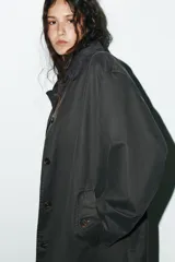 Gabardina larga color gris oscuro con efecto encerado, cuello solapa de pana, manga larga, bolsillos laterales con solapa y cierre frontal con botones ocultos.