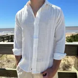 Camisa de manga larga con cuello clásico y cierre frontal de botones. Confeccionada en tejido de lino con textura visible, presenta un corte boxy y mangas arremangadas.
