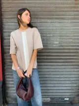 Buzo de algodón color beige, con cuello redondo, mangas cortas y tres franjas verticales en tonos blanco y beige en el frente.