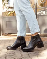 Botinetas de cuero negro con diseño de punta cuadrada y taco bloque. Presentan cierre lateral para facilitar el calce y una textura sutil en la puntera.